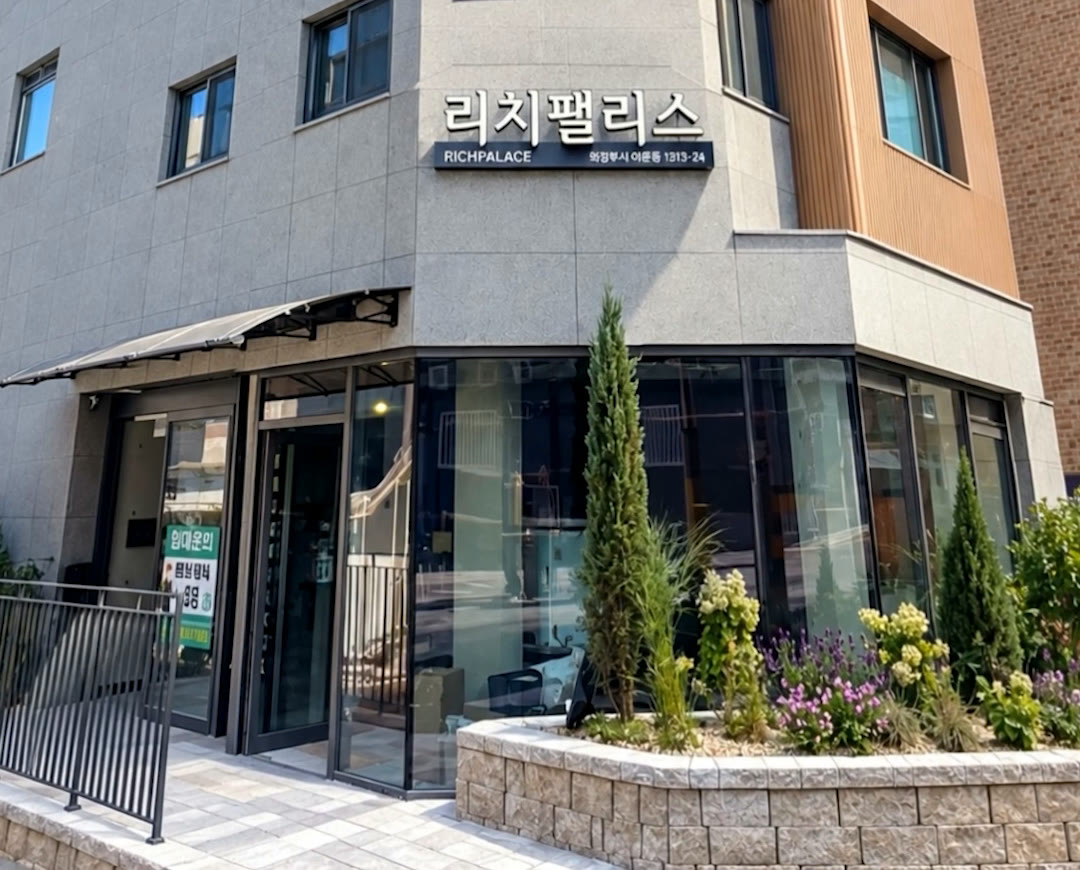 리치팰리스 입구 — 통유리 로비와 캐노피, 돌 화단